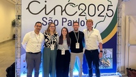 Fünf Teilnehmende posieren vor einem Banner der cinC 2025 Konferenz in São Paulo.