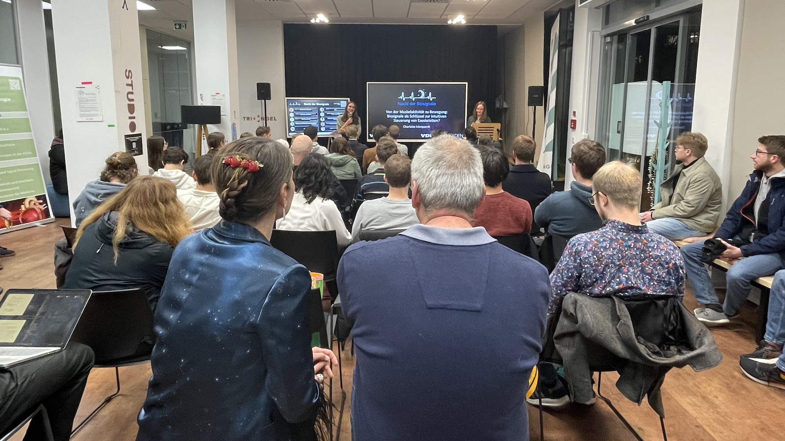 Publikum hört Vortrag zu Biologie und Bewegung in einem modernen Veranstaltungsraum.